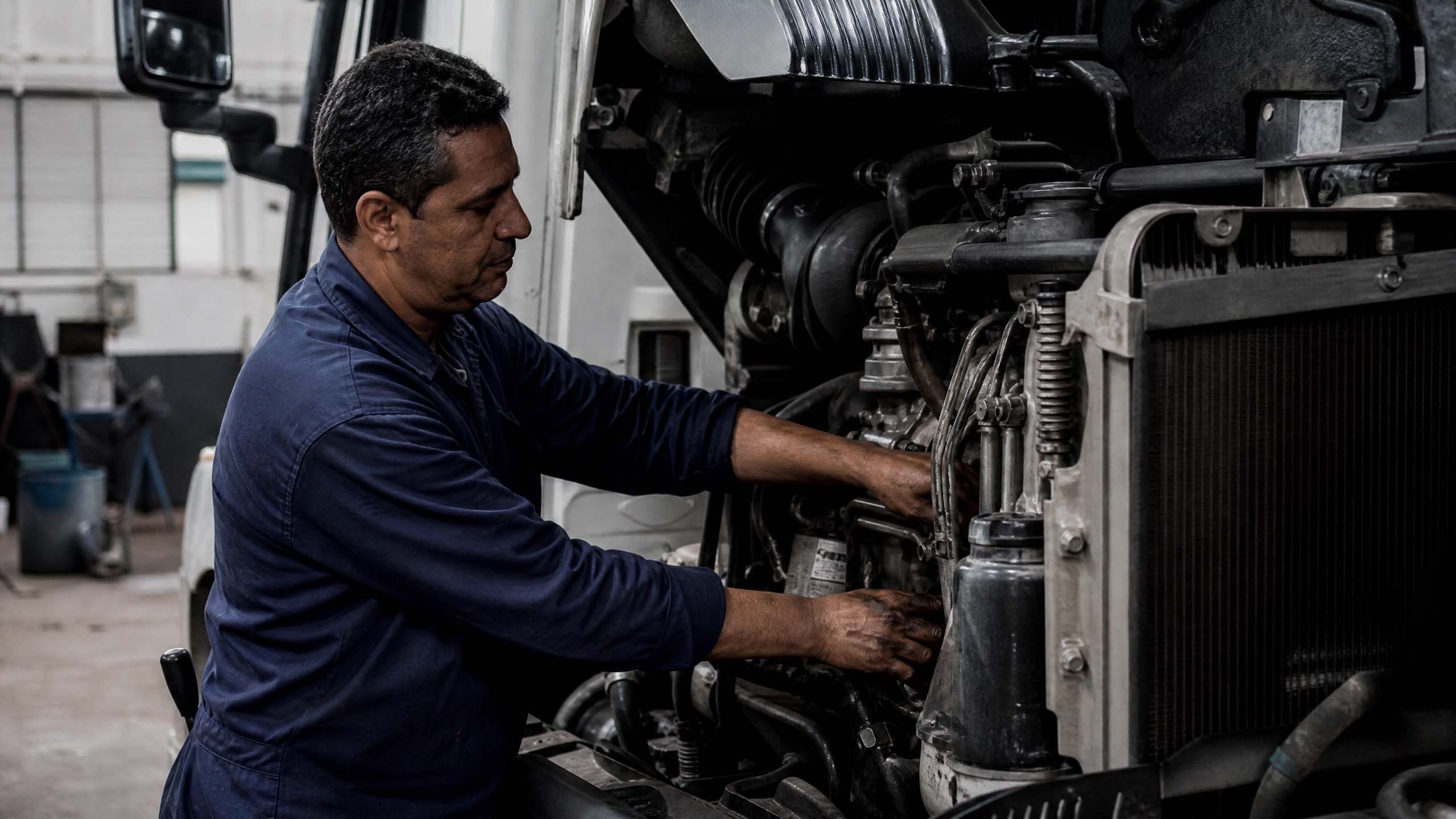 Mecânico realizando manutenção preventiva em caminhão Mercedes-Benz em oficina