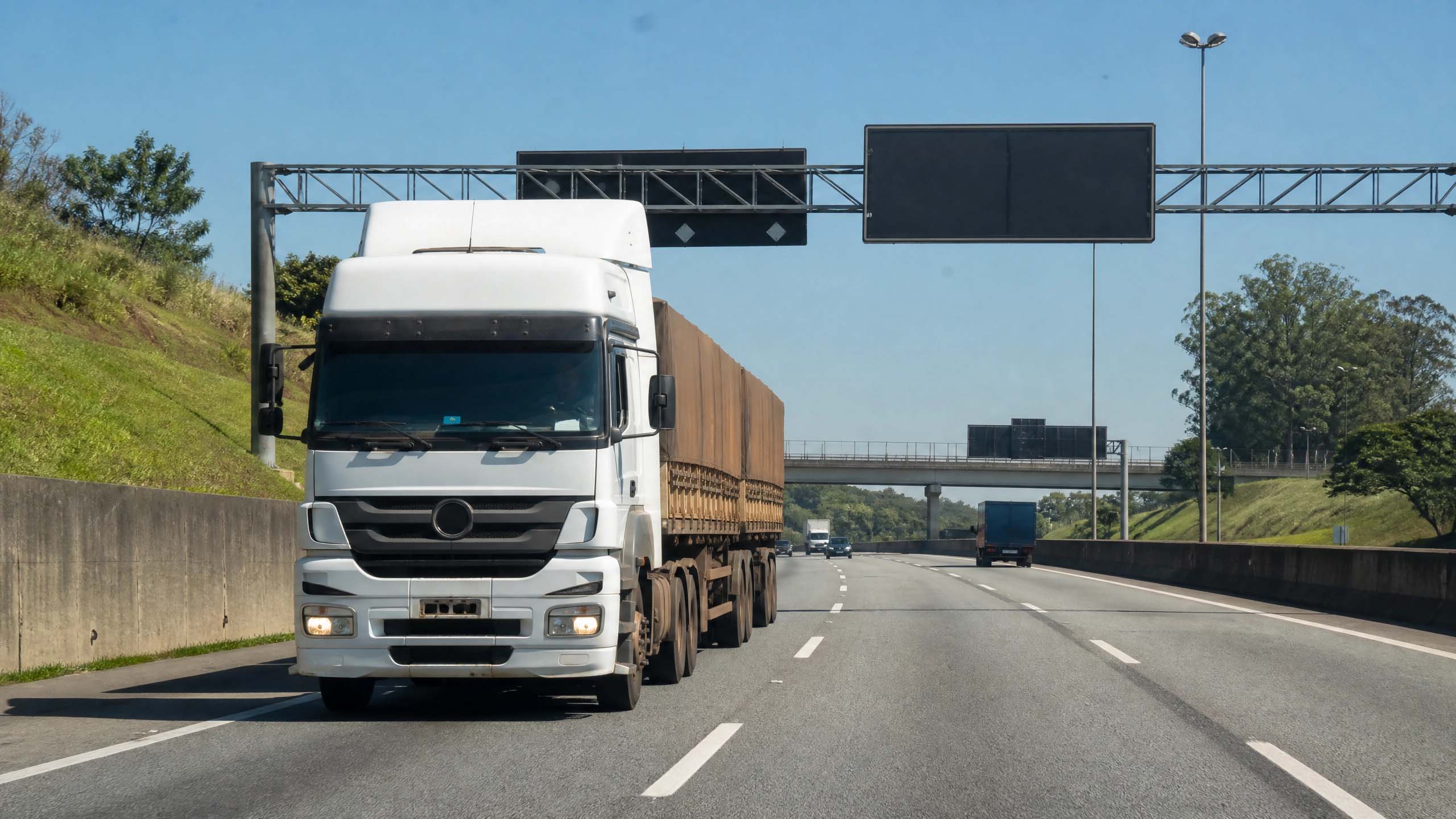 Caminhão de linha pesada em rodovia asfaltada com placas de sinalização